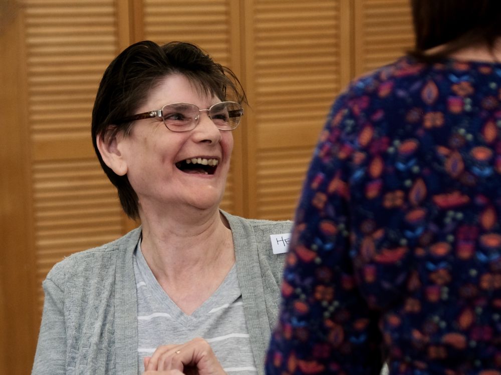 A woman in a grey cardigan laughing out loud