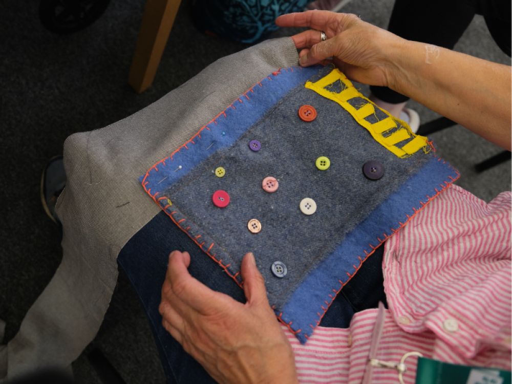 A top down shot of a textile artwork with patches and buttons on
